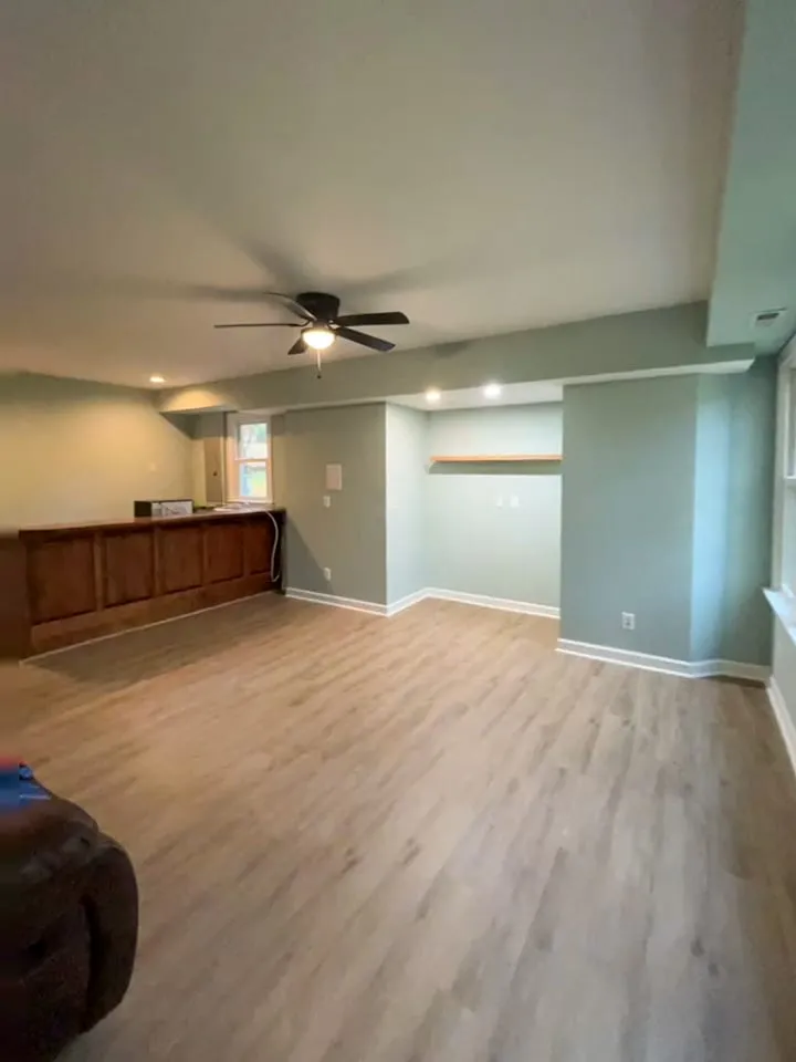 Wide finished living room view with updated flooring, painted walls, and bar area