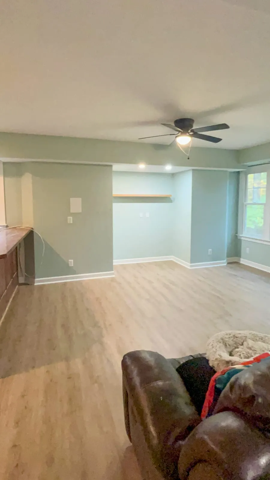 Finished living room remodel with light wood flooring, painted walls, and window view