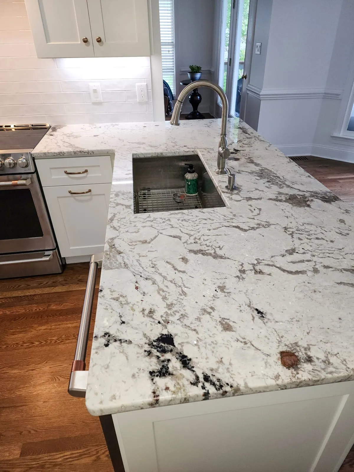 Kitchen island sink with quartz countertop, faucet, and white tile backsplash