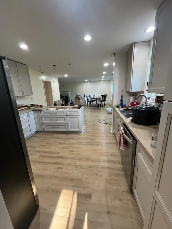 Open kitchen remodel with gray cabinets, long counter runs, and light wood flooring