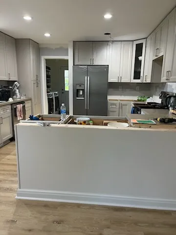 Kitchen peninsula with gray cabinet base and remodel materials during finishing