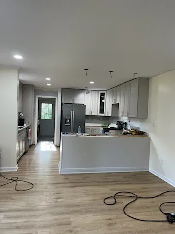 Kitchen remodel wide view with peninsula, gray cabinets, and open floor area