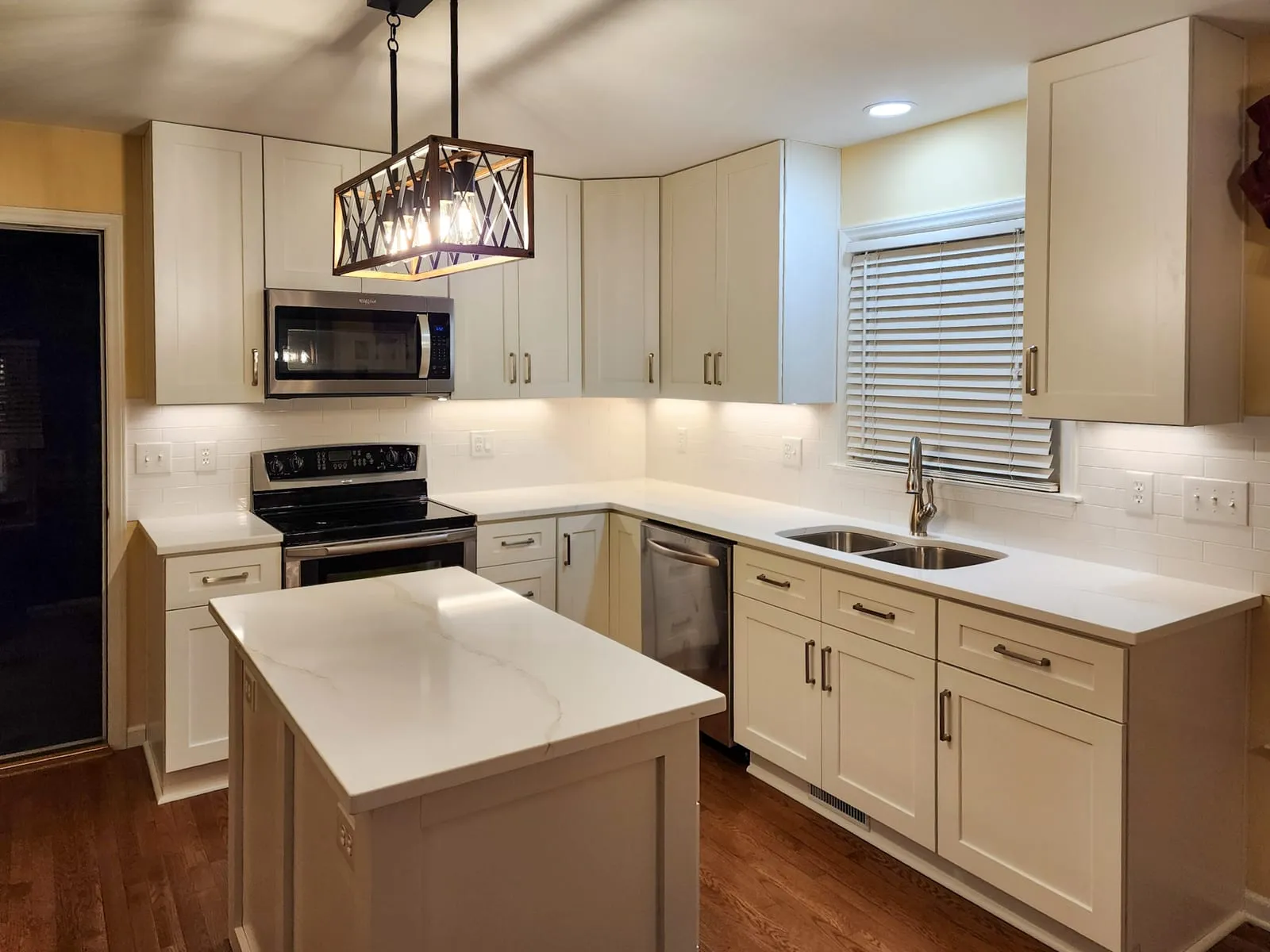 Kitchen remodel range wall with white cabinets, tile backsplash, and sink window