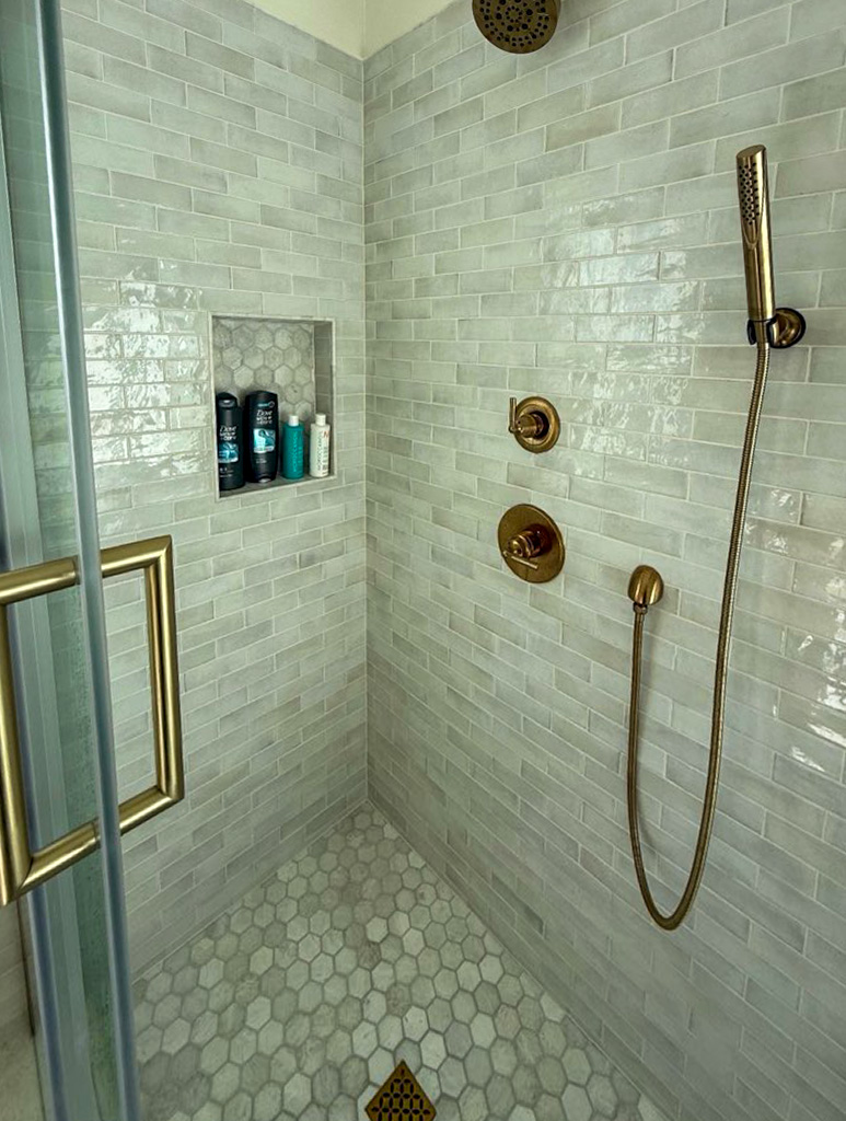 Bathroom shower tile detail with brass fixtures and niche