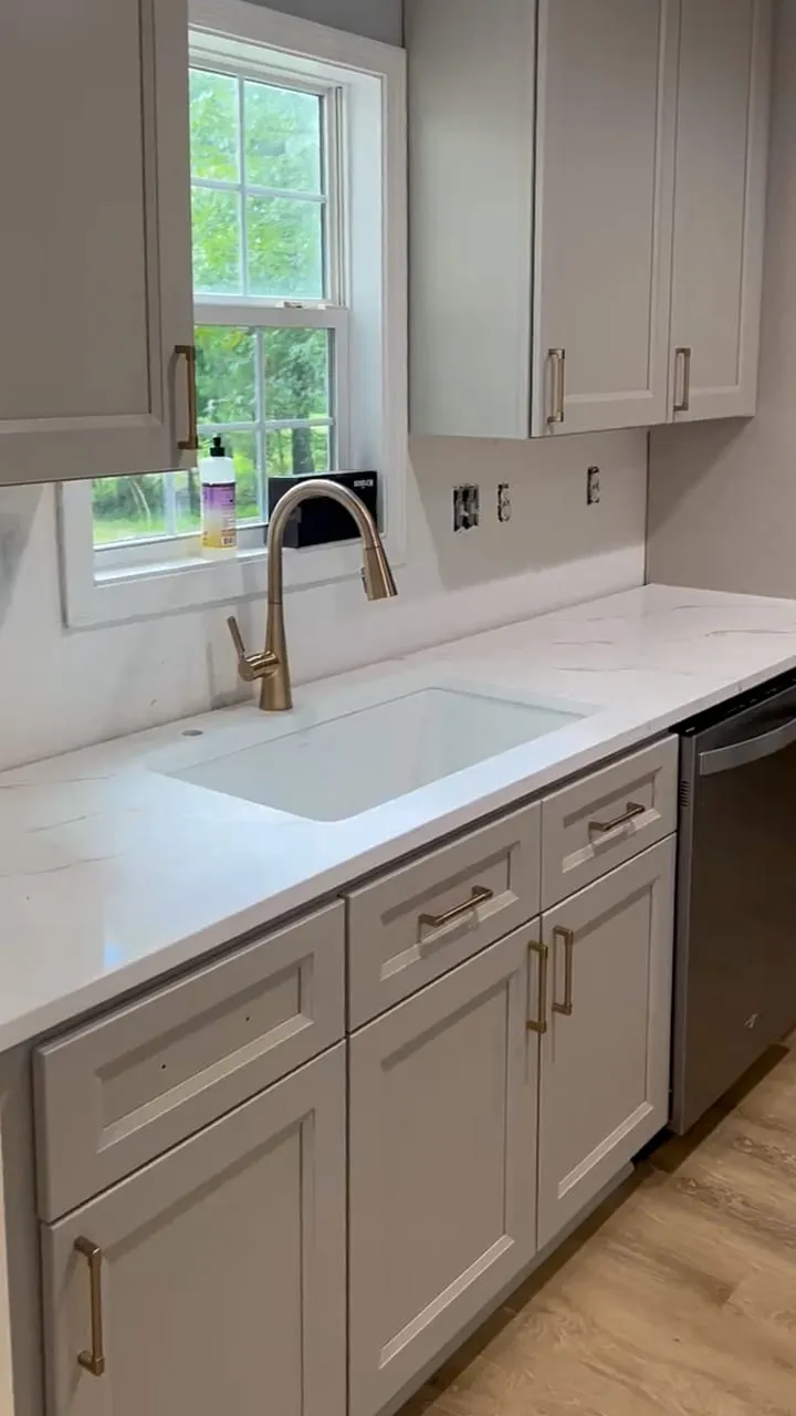 Kitchen sink wall with window, white cabinets, and new countertop