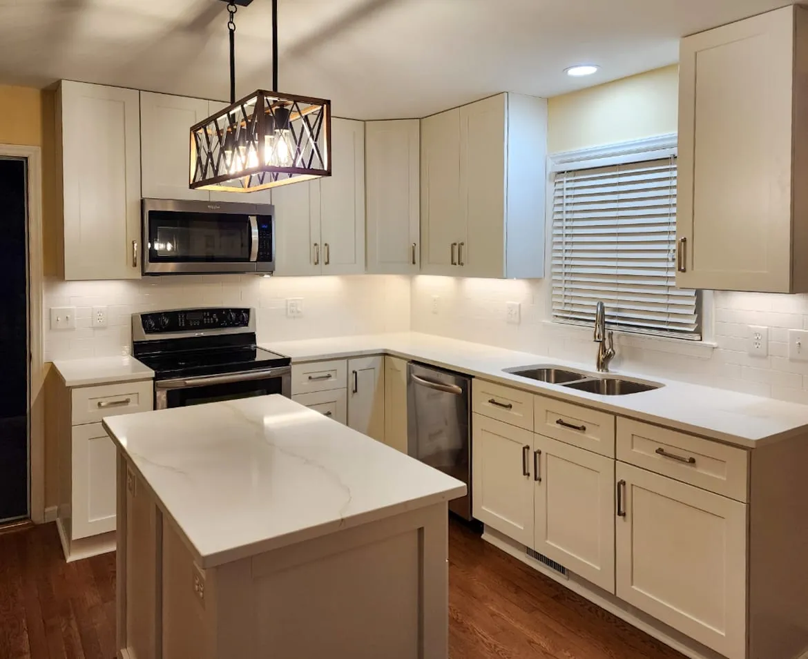 Kitchen remodel with white cabinets, island, tile backsplash, and box pendant light